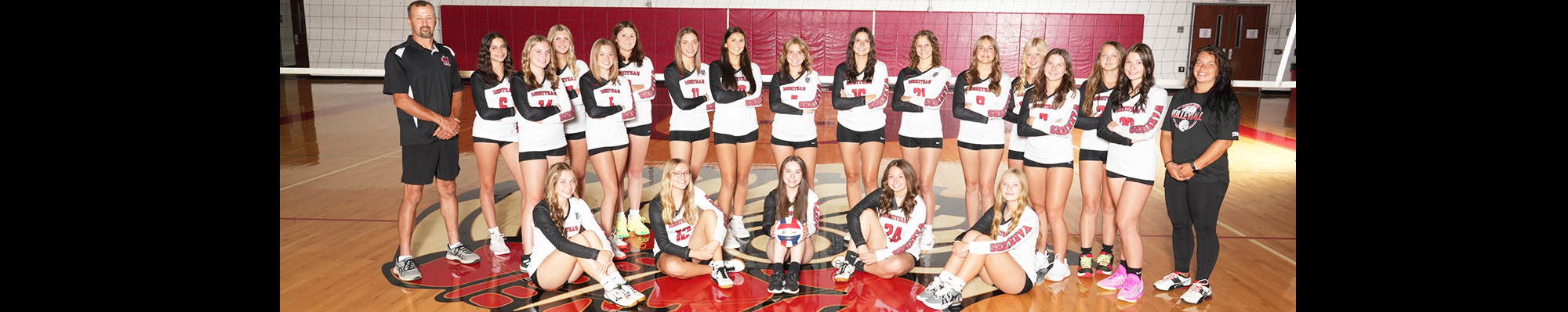 Volleyball team in the gym with coaches