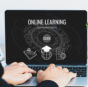 Hands hovering over laptop keyboard. Online Learning is shown on the laptop screen.
