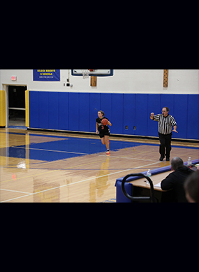 Girls basketball player with ball and referee near by