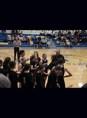 Girls basketball team on the side of the court